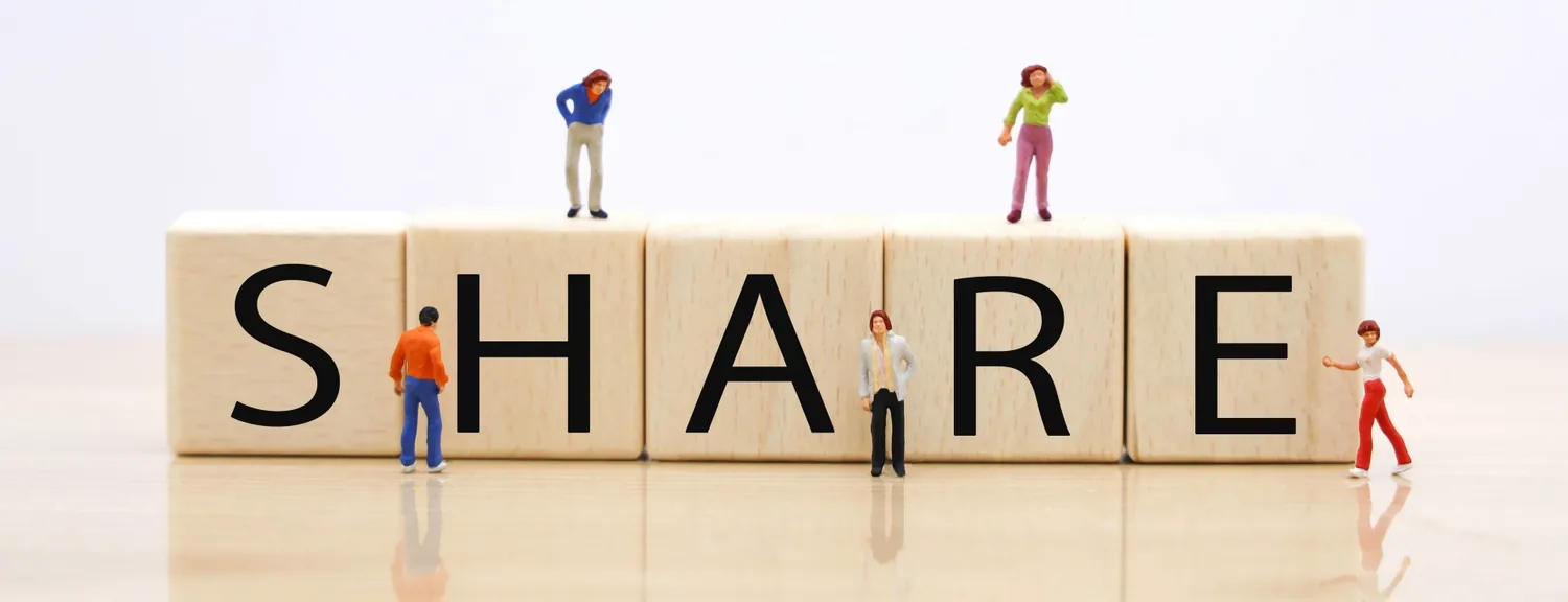 「SHARE」と並べた積み木と、その上に立つミニチュアの人形