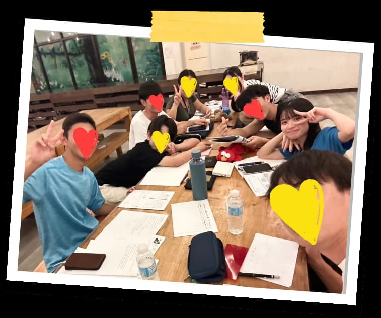 語学学校で机を囲んでピースをする留学仲間たち